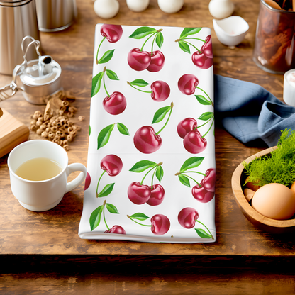 White tea towel featuring a vibrant cherry print with green leaves.