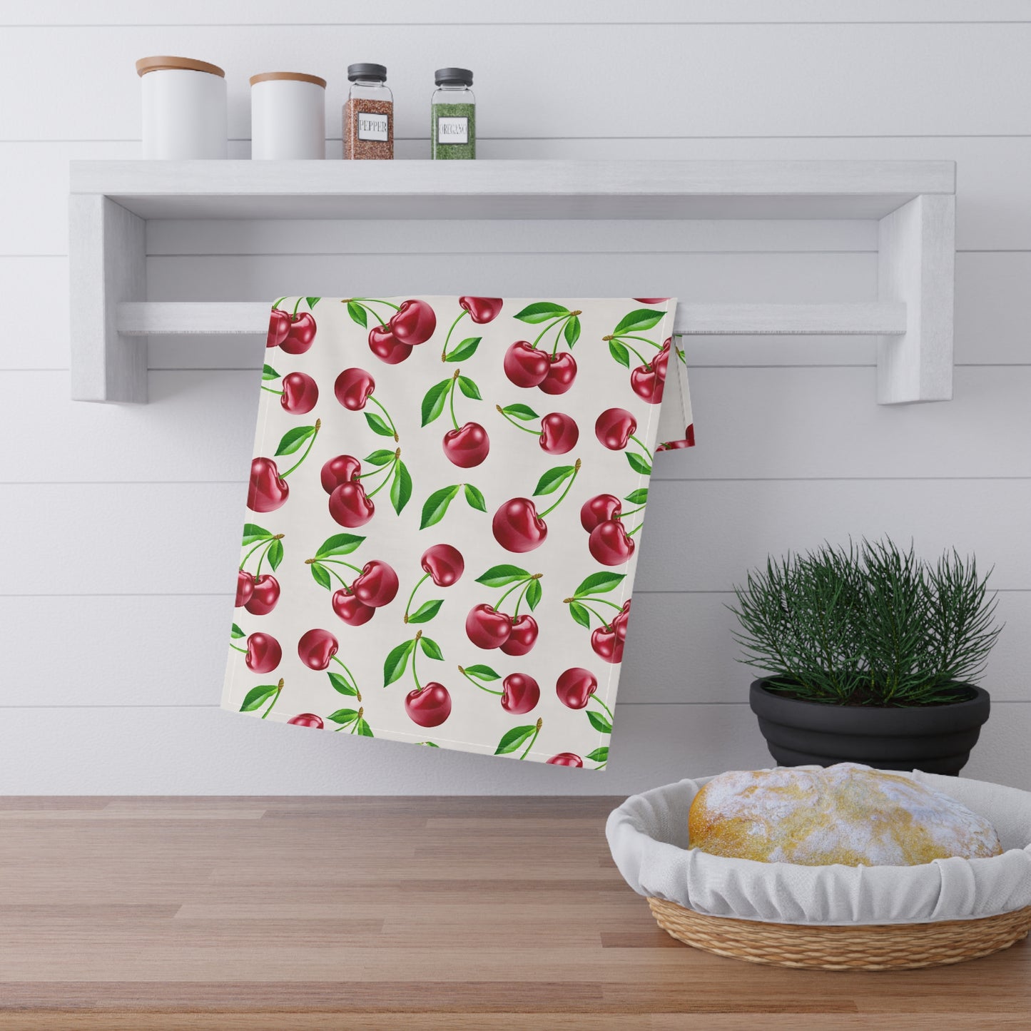 White tea towel featuring a vibrant cherry print with green leaves.